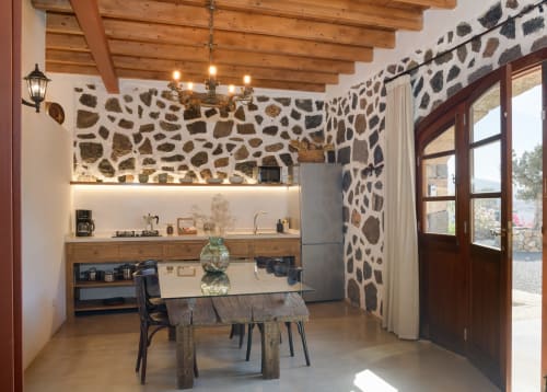 La Cochera cottage kitchen-dining area with stone walls, wooden beams, and garden views in Yaiza