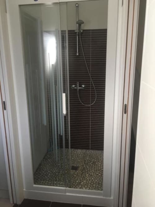 Douche moderne aux carreaux noirs horizontaux et sol en galets à l'appartement Nano House de Bègles, France