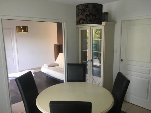 Appartement Nano House à Bègles avec table à manger ronde, chaises noires et vue sur le jardin par les portes vitrées