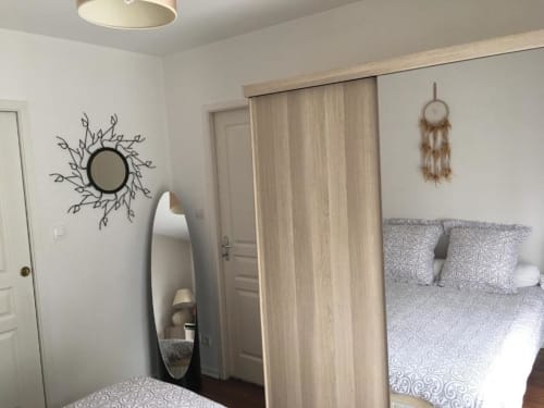 Chambre moderne à l'appartement Nano House Bègles avec miroir décoratif, attrape-rêves et portes coulissantes en bois clair