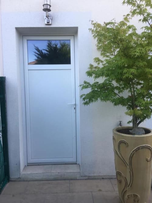 Porte bleu clair moderne avec fenêtre donnant sur le jardin à l'appartement Nano House à Bègles, avec arbre en pot et blanc