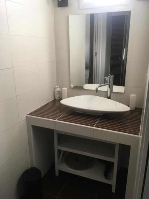 Lavabo et meuble-vasque modernes à l'appartement Nano House de Bègles avec carrelage blanc et plan de travail en bois foncé