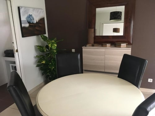 Salle de réunion moderne à l'appartement Nano House à Bègles avec table ronde blanche, chaises noires et vue sur le jardin