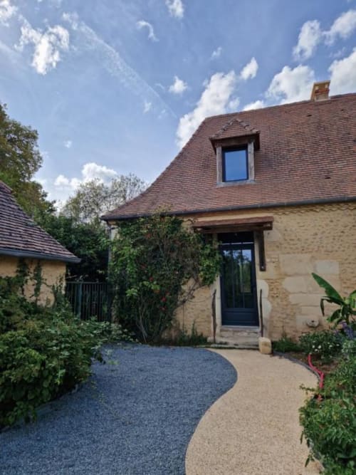 Gîte Escapade au Domaine de la Grande Décision : chalet en pierre, toit mansardé, entrée couverte de lierre et allée gravillonnée