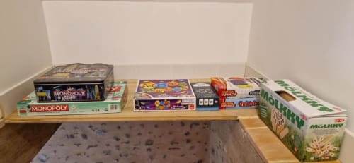 Jeux de société et puzzles rangés sur une étagère en bois à la Gîte Escapade du Domaine de la Grande Décision, La Douze