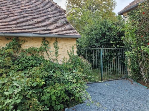 Entrée de chaumière luxuriante couverte de lierre avec portail métallique décoratif au Domaine de la Grande Décision, La Douze