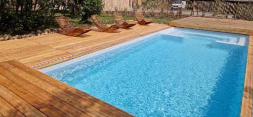 Piscine rectangulaire aux eaux cristallines et terrasse en bois du gîte Domaine de la Grande Décision à La Douze