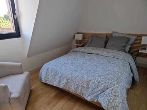 Chambre moderne du gîte Escapade avec parure de lit bleue motifs, tête de lit en bois et plafond mansardé au Domaine de la