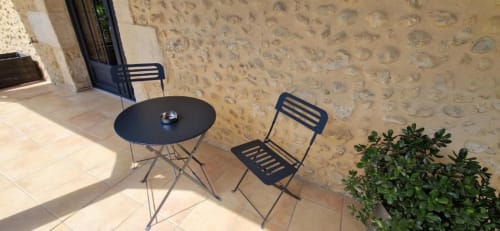 Terrasse du Gîte Cocoon with black round table, metal chairs, and stone walls at Domaine de la Grande Décision, La Douze