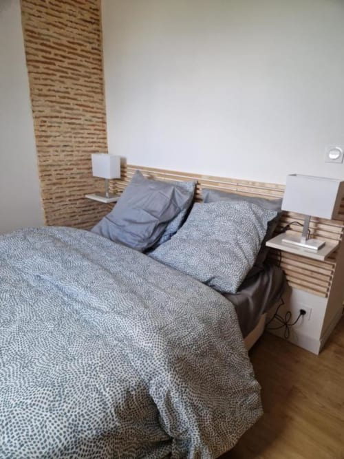 Modern bedroom with wooden accent wall, blue-grey bedding, and bedside tables at Gîte Cocoon, La Douze