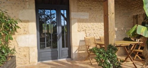 Gîte Cocoon terrace at Domaine de la Grande Décision with wooden furniture, stone walls, and garden views in La Douze