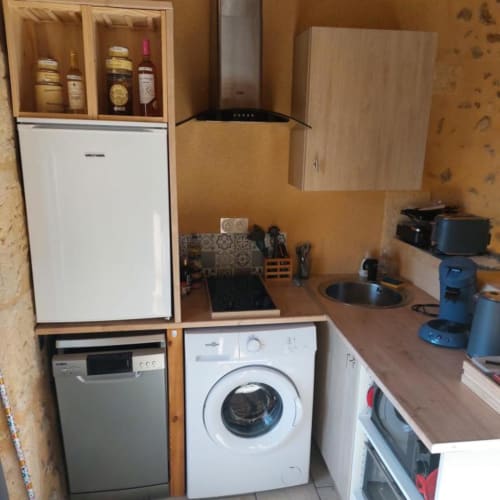 Compact kitchen in Gîte Cocoon cottage with appliances, cooktop, and wine storage cabinet