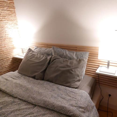 Bedroom in Gîte Cocoon cottage at Domaine de la Grande Décision, featuring wooden bed frame with gray bedding and dark