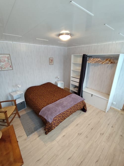 Chambre moderne de l'appartement Accolade à Châteaudun avec lit, armoire et parquet en bois