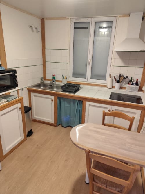 Cuisine lumineuse avec mobilier en bois, armoires blanches et table à manger de l'appartement Accolade, Châteaudun