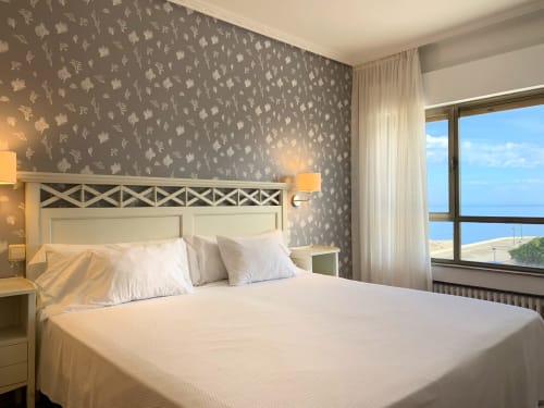 Elegante habitación del Hotel Playa de Los Locos en Suances con vistas al mar, papel tapiz estampado y mobiliario moderno