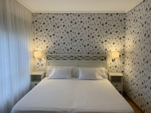 Habitación moderna del Hotel Playa de Los Locos en Suances con papel tapiz floral, ropa de cama blanca y lámparas de lectura