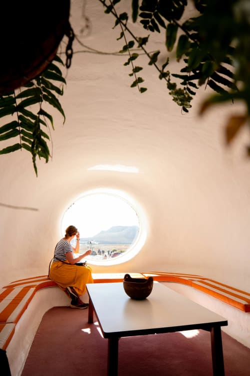 Woman at Finca de la Geria in Yaiza viewing landscape through circular window with hanging plants