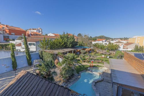 Aerial view of Ninho Saloio hotel courtyard with blue pool, lush gardens, and traditional Portuguese architecture in Venda do