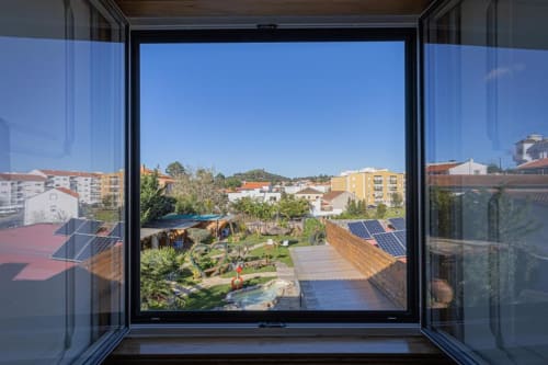 View from Seagull Studio window at Ninho Saloio hotel showing garden, lake, solar panels, and residential buildings in Venda