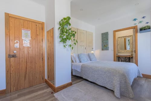 Premium bedroom at Ninho Saloio with queen bed, wooden doors, and hardwood floors in Venda do Pinheiro