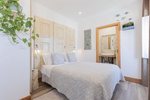 Bright bedroom at Ninho Saloio with queen bed, white walls, wooden accents, and ensuite bathroom in Venda do Pinheiro