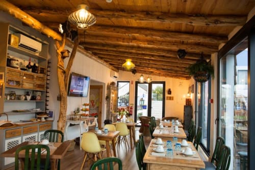 Ninho Saloio's rustic dining room with wooden beams, set tables, and modern furnishings in Venda do Pinheiro