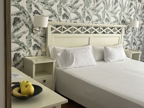 Habitación moderna del Hotel Playa de Los Locos con papel pintado tropical, cama color crema, ropa de cama blanca y vistas al jardín en Suances