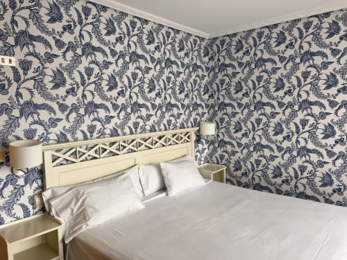 Elegante habitación del Hotel Playa de Los Locos en Suances con papel pintado floral azul, cabecero crema y ropa de cama blanca