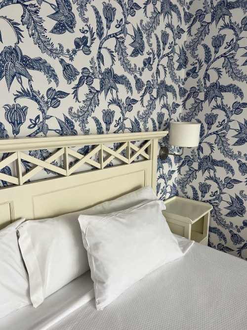 Elegante dormitorio del Hotel Playa de Los Locos en Suances con papel pintado botánico azul marino y cama crema