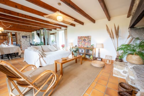 Spacieux séjour ouvert au gîte Espace Ker Gana à Plourin avec poutres apparentes, canapé blanc et mobilier en bois
