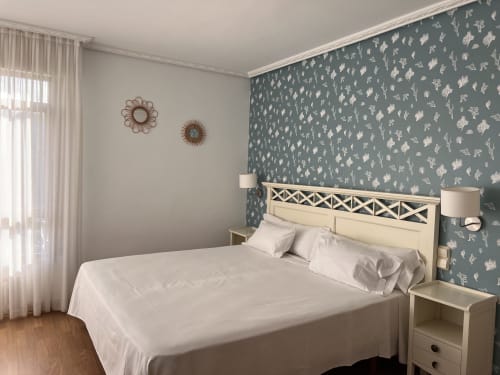 Luminosa habitación del Hotel Playa de Los Locos con papel tapiz botánico, cabecero crema y vistas al mar en Suances