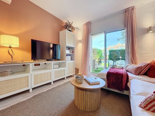Dormitorio moderno en Estartit Rental con pared de acento melocotón, TV de pantalla plana, vistas al mar y muebles contemporáneos