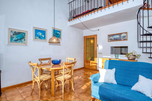 Bright apartment living room in Calella with blue sofa, wooden dining table, and marine-themed artwork on white walls