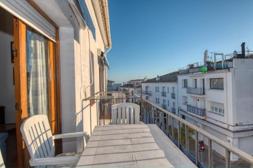Sunny balcony of beachfront apartment in Calella, Palafrugell with sea views and white chair overlooking Mediterranean