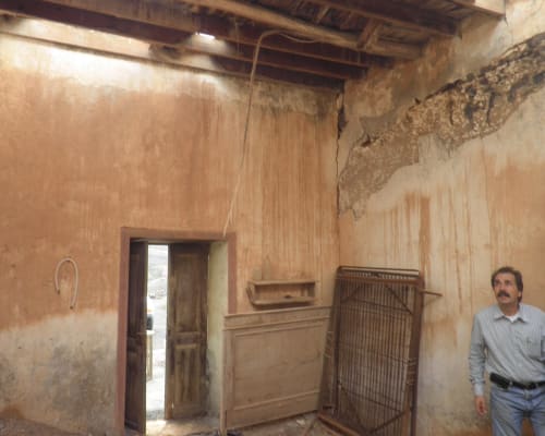 Rustic room interior at Finca de La Geria in Yaiza showing deteriorated walls, wooden fixtures, and exposed beams