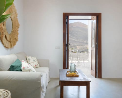 Modern living room at Finca de La Geria with view of volcanic mountain landscape through open doors, Yaiza
