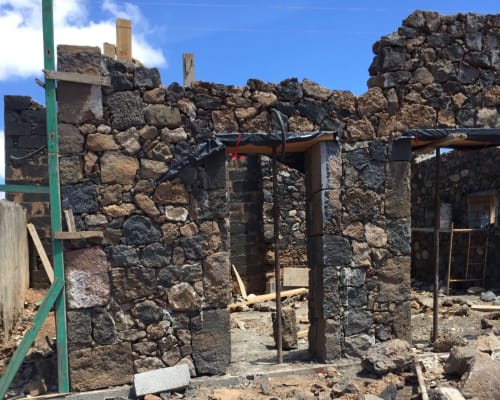 Historic stone ruins with wooden beams at Finca de La Geria in Yaiza under clear blue sky