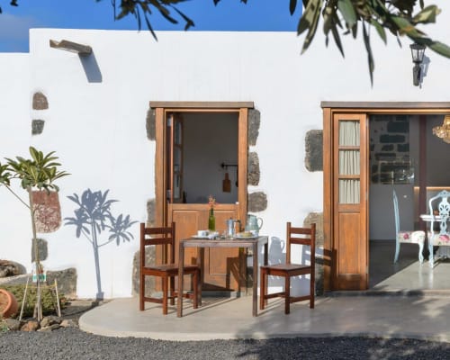 Whitewashed patio at Finca de La Geria with wooden door, dining table, and potted plants in Yaiza