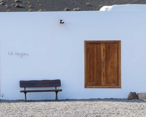 Rustic wooden bench and door against white wall at Finca de La Geria in Yaiza