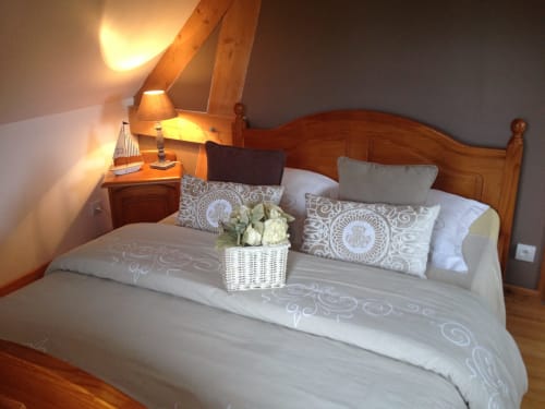 Chambre de charme au Domaine du Clos Mahiel avec lit en bois, parures de draps, coussins, décoration soignée, endroit calme et somptueux