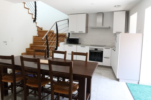 Cuisine de cottage moderne avec coin repas, escalier en bois et armoires blanches à Au Bord de la Dunière, Sainte Sigolène