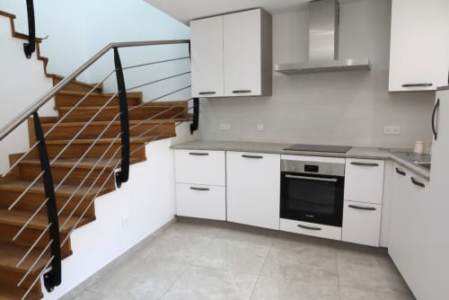 Cuisine moderne blanche avec escalier en bois du gîte Au Bord de la Dunière à Sainte-Sigolène