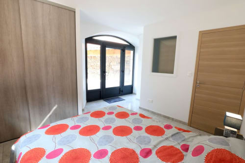 Chambre moderne à Au Bord de la Dunière avec literie à motifs rouges et vue sur la rivière par portes noires