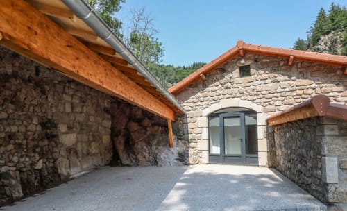 Entrée du gîte Au Bord de la Dunière avec poutres apparentes, portail voûté et montagnes boisées à Sainte-Sigolène