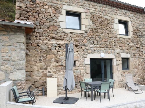 Patio en pierre du Au Bord de la Dunière avec table, chaises et parasol à Sainte Sigolène