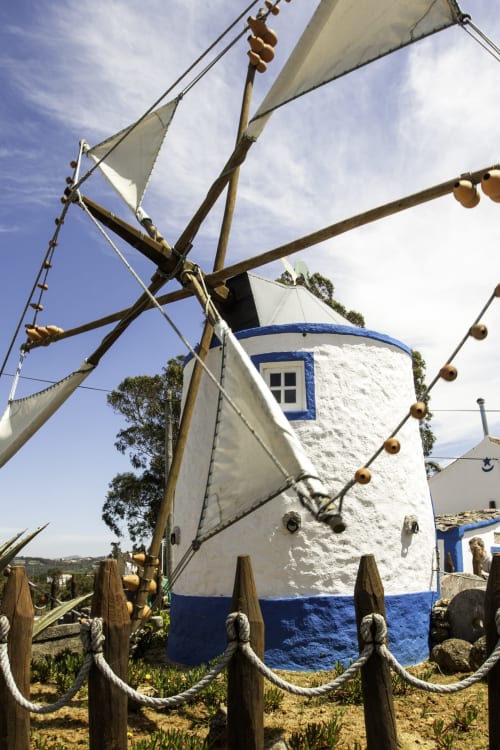 Moinho tradicional branco e azul com velame no hotel Ninho Saloio em Venda do Pinheiro, Portugal