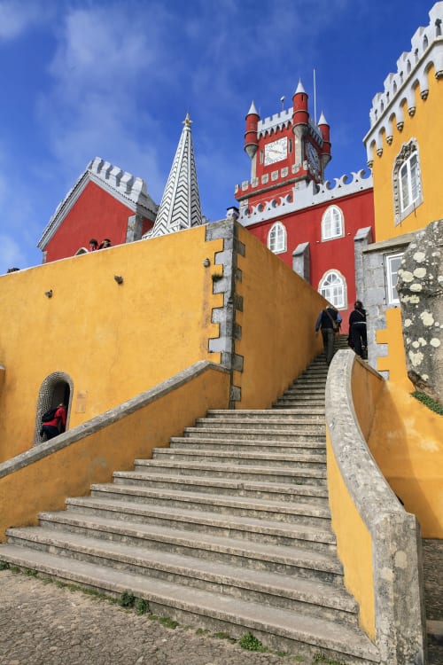 Escadaria colorida do Hotel Palace em Venda do Pinheiro com paredes amarelas, torre vermelha e céu azul