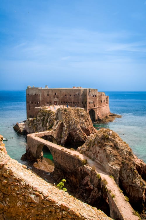 Fortaleza histórica de pedra sobre penhasco rochoso costeiro com vista para as águas turquesas do Mediterrâneo perto de Venda do Pinheiro, Portugal