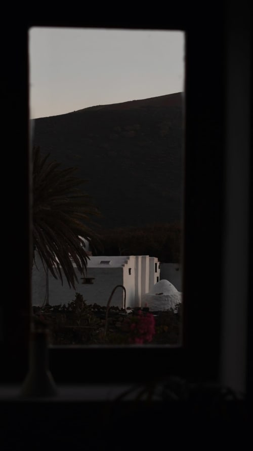 Vista a través de la puerta de Finca de La Geria con edificios blancos y paisaje volcánico oscuro cerca de Yaiza, Lanzarote